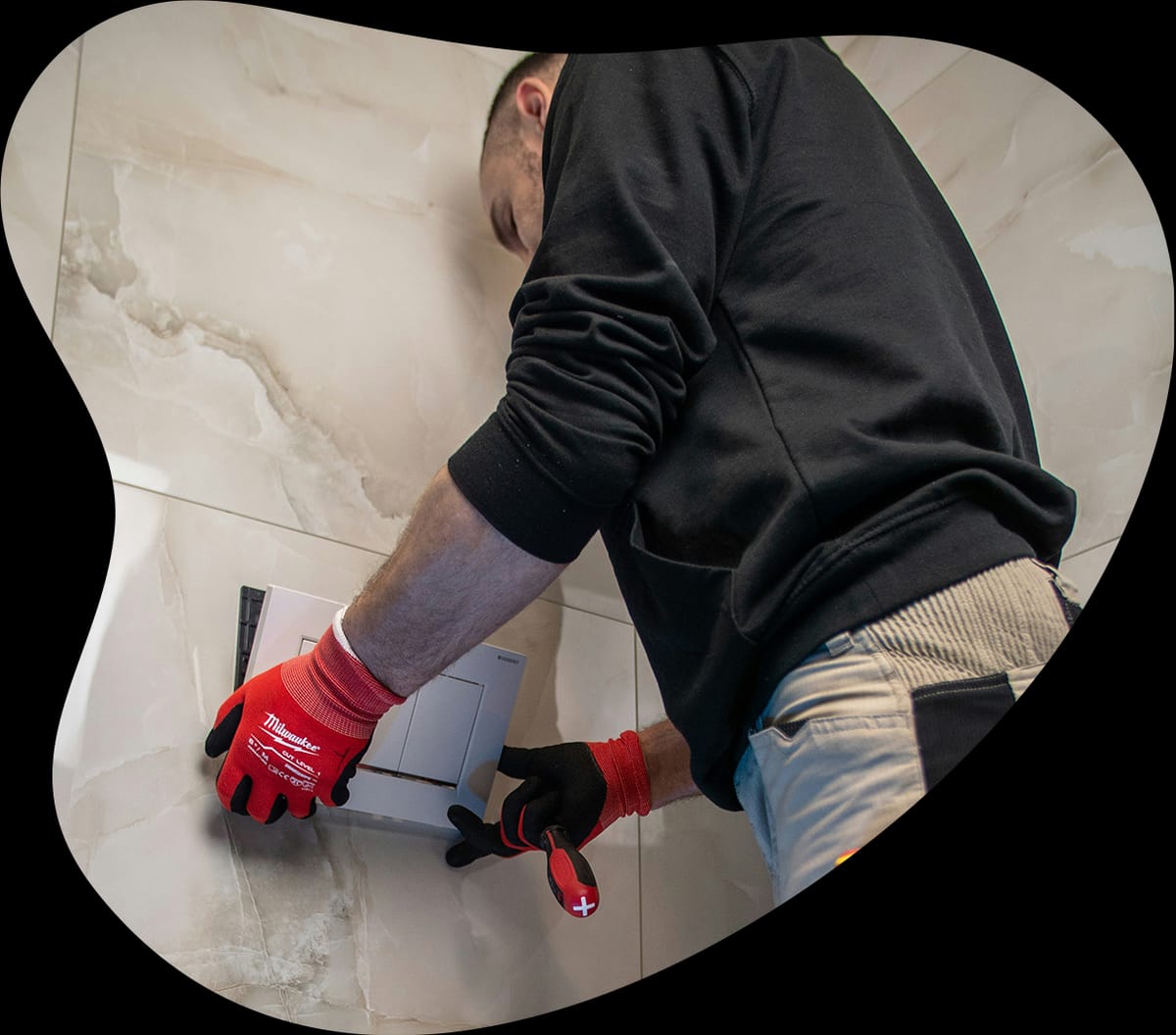 Plumber fitting a flush plate on a tiled wall